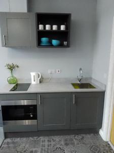 una cocina con armarios grises y fregadero en Piccadilly Apartments, en Bradford