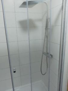 a shower with a glass door with a hose at Piccadilly Apartments in Bradford