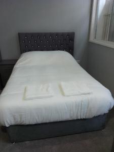 a bed with white sheets and a black headboard at Piccadilly Apartments in Bradford