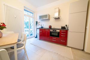 cocina con armarios rojos, mesa y comedor en FHRE Premium Apartments D7 Weimar 3 Bedroom, en Weimar