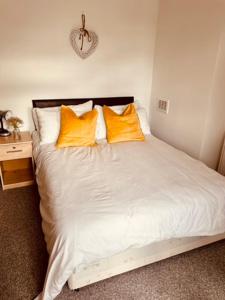 Bett mit gelben Kissen auf einem Zimmer in der Unterkunft Two Bedroom, Off-road Parking in Ludgershall