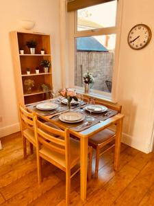 a dining room table with chairs and a clock on the wall at Two Bedroom, Off-road Parking in Ludgershall