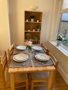 una mesa con platos y un jarrón de flores. en Two Bedroom, Off-road Parking en Ludgershall