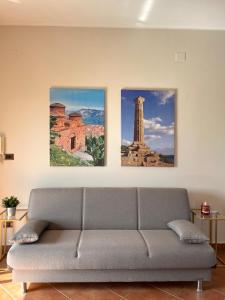 three paintings on a wall above a couch in a living room at La casa di Isa in Lamezia Terme