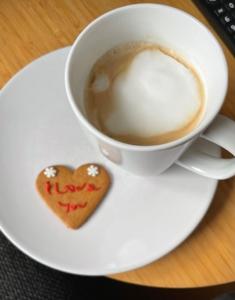 a cup of coffee and a heart shaped cookie on a plate at Two Bedroom, Off-road Parking in Ludgershall