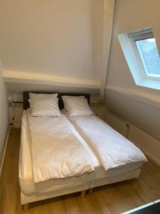 łóżko z białą pościelą i poduszkami w pokoju w obiekcie 2 pièces les écuries du château w mieście Bonnelles