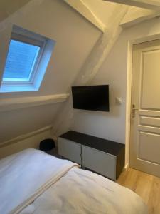 a bedroom with a bed and a flat screen tv at 2 pièces les écuries du château in Bonnelles