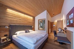 a bedroom with a large bed with a wooden wall at Boutique Hotel Schraemli's Lengmatta in Davos