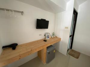 Zimmer mit einem hölzernen Schreibtisch und einem TV an der Wand in der Unterkunft White house bailan resort in Ko Chang