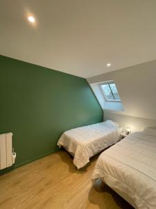a bedroom with two beds and a green wall at Gîtes de Cohuta in Montfort-sur-Meu