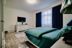 a bedroom with a bed and a tv and a window at Galiceanu Apart Deluxe in Bistriţa