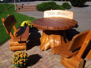 een houten tafel en twee stoelen en een houten tafel en bank bij Gaststätte & Pension Alte Mühle in Dorfchemnitz