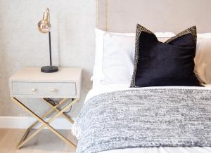 a bed with a black pillow and a nightstand with a lamp at Luxury 2 Bedroom Apartment Near Train Station in Welwyn Garden City