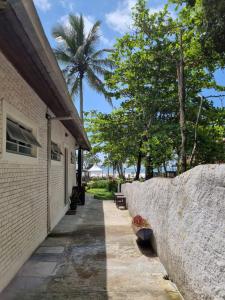 eine Steinmauer neben einem Gebäude mit einer Palme in der Unterkunft Yabás Praia in Ubatuba