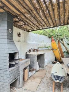 une cuisine extérieure avec un four en briques et une planche de surf dans l'établissement Yabás Praia, à Ubatuba