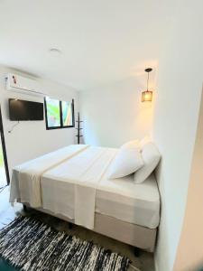 um quarto branco com uma cama e uma televisão em Yabás Praia em Ubatuba