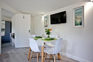 a white dining room with a white table and white chairs at The Cabin at Hillhead farm in Saint Columb Major
