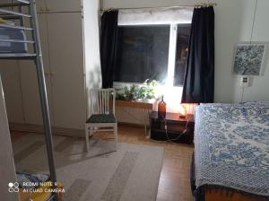 ein Schlafzimmer mit einem Bett, einem Fenster und einem Stuhl in der Unterkunft Old Cozy Wood House in Rovaniemi