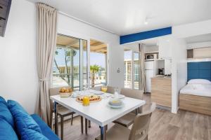 a dining room with a white table and a blue couch at Mobile Homes in Camping Omisalj, island Krk, with swimmingpool in Omišalj