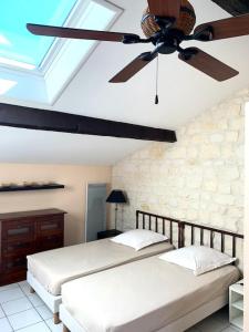 1 dormitorio con 2 camas y ventilador de techo en Maison de ville confortable avec piscine, en Pons