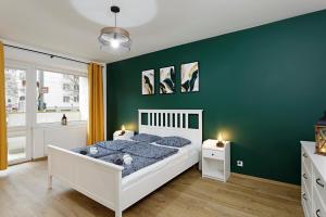 a bedroom with a white bed and a green wall at Na zielonym Widoku in Wrocław