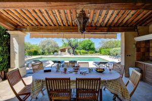 een terras met een tafel en stoelen en een zwembad bij Les Chambres du Perussier in Cucuron
