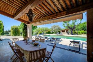 een terras met een tafel en stoelen en een zwembad bij Les Chambres du Perussier in Cucuron