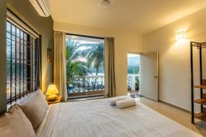 a bedroom with a bed and a large window at Morii homes River view # Siolim 