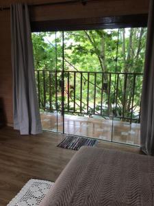 1 dormitorio con una gran puerta de cristal que da a un balcón en Estância Liberdade, en Santo Antônio do Pinhal
