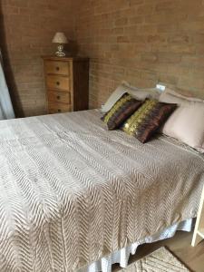 um quarto com uma cama com almofadas e uma parede de tijolos em Estância Liberdade em Santo Antônio do Pinhal