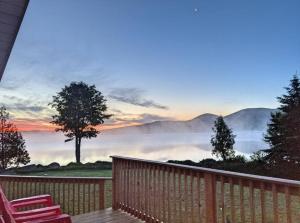 a deck with two chairs and a view of a foggy valley at Lakefront Stunning Home, only 30 min to Sugarloaf! in New Portland