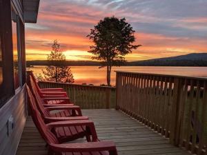 a row of chairs sitting on a porch watching the sunset at Lakefront Stunning Home, only 30 min to Sugarloaf! in New Portland