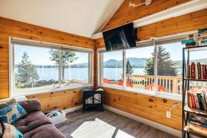 a living room with a couch and windows at Lakefront Stunning Home, only 30 min to Sugarloaf! in New Portland
