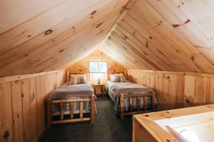 1 dormitorio con 2 camas en una cabaña de madera en Lakefront Stunning Home, only 30 min to Sugarloaf! en New Portland