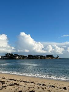 a beach with the ocean and houses in the distance w obiekcie Corniche - Bénodet w mieście Bénodet