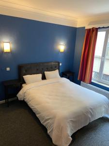 um quarto com uma grande cama branca com paredes azuis em Hotel Windsor em Bruxelas