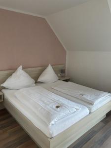 Una cama blanca con sábanas blancas y almohadas. en Hotel Bismarckhöhe, en Tecklenburg