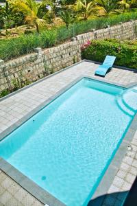 a swimming pool with a blue chair and a bench at RESIDENCE SAPHIR in Mahajanga