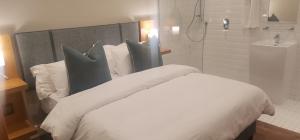 ein Schlafzimmer mit einem weißen Bett mit Kissen und einer Dusche in der Unterkunft Sugar Hotel in Kapstadt