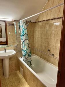 a bathroom with a tub and a sink and a shower curtain at Christina Apartment in Laplandia in Pamporovo