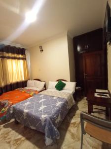 1 dormitorio con 2 camas y mesa en Jowillis Hotel, en Kabale