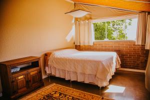 ein kleines Schlafzimmer mit einem Bett und einem Fenster in der Unterkunft Sítio Crescer in Garibaldi