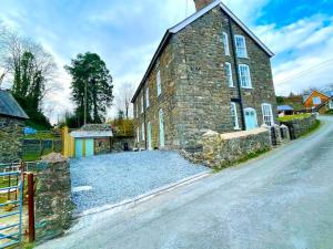 um velho edifício de pedra com uma cerca em frente em Castle Buildings Cottage1 em Llanrhaeadr-ym-Mochnant