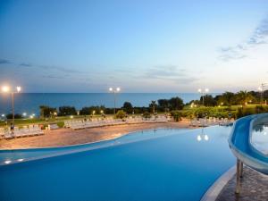 una piscina con vista sull'oceano di notte di Serenusa Resort a Licata