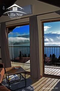 a room with a balcony with a view of the ocean at Villa Nur - Lake View Apartaments in Mavrovi Anovi