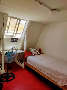 Habitación pequeña con cama y ventana en Backpackers House - Near The Airport en Santiago