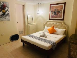 Dormitorio pequeño con cama con almohadas de color naranja y blanco en O Boutique Hotel (Free Breakfast), en Tagaytay