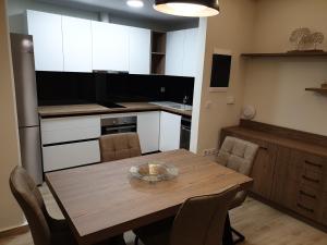 cocina con mesa de madera con sillas y TV en Olive Deluxe Apartment en Kardítsa