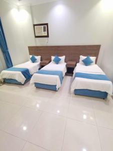 Habitación con 3 camas y almohadas azules y blancas. en سارة للشقق المفروشة - الحمدانية جدة en Ḩayy aş Şāliḩīyah