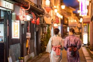 dos mujeres caminando por una calle por la noche en Iwayu en Misasa